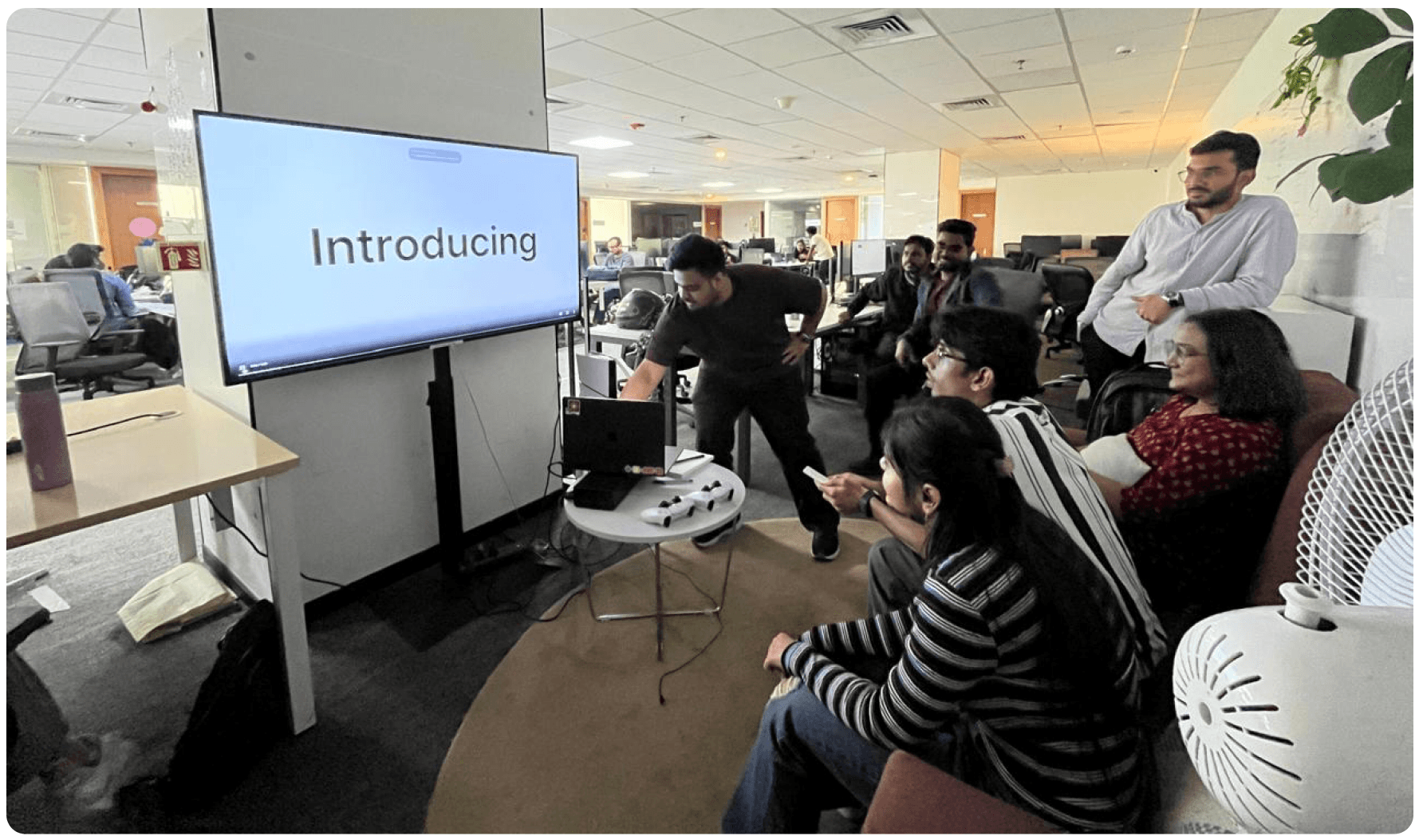 A team gathered around a screen reading 'Introducing', presenting the design system to the wider team
