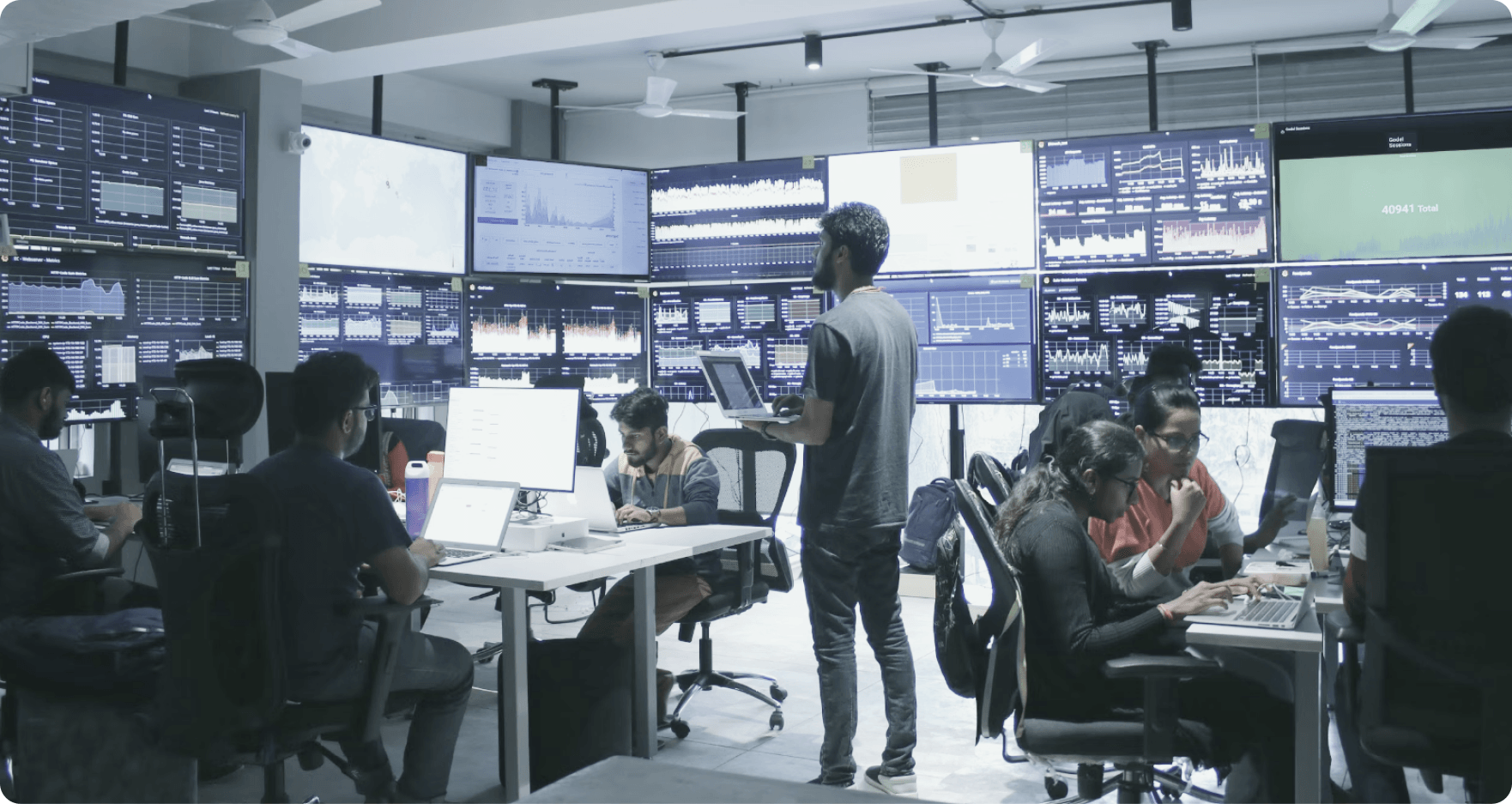 Engineering team working across monitoring dashboards in the operations room